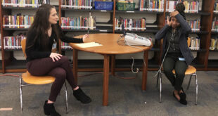 Allison Ventrone and fellow student Camisha Hatcher at a table in the library of a local elementary school